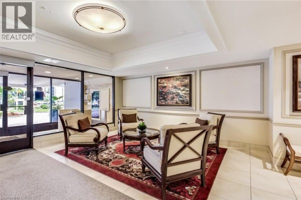 Building entrance lobby with upholstered chairs, a patterned rug, and framed artwork. - 2185 Marine Drive Unit# 202, Oakville