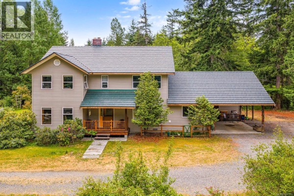 Front view of the two-story house with a porch and landscaped yard. - 2187 May Rd, Courtenay