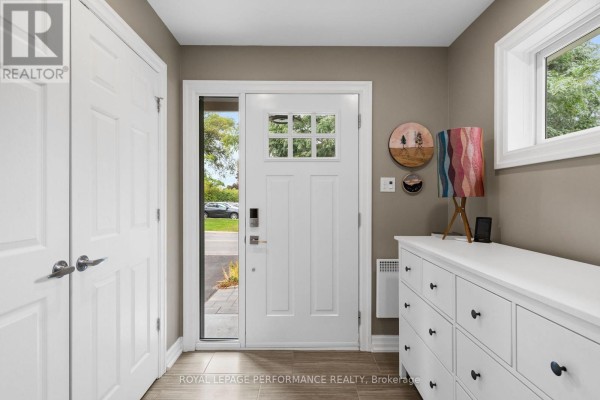 Entranceway with a white front door, sidelight window, two closets, and a console table. - 2189 Blossom Drive, Ottawa
