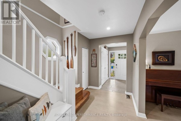 Hallway with a staircase, bench, coat hooks, and a view towards the front entrance. - 2189 Blossom Drive, Ottawa
