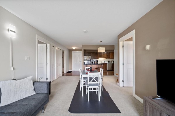 Living room with a television, sofa, rug, and a door leading to a balcony. - 219 32725 George Ferguson Way, Abbotsford