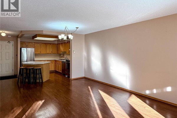 View of kitchen and dining area with island, stainless steel appliances, and hardwood floors. - 219 960 Assiniboine Avenue E, Regina