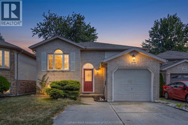 Front exterior of a beige brick house with a red front door and attached garage. - 219 Greenfield Lane, Chatham
