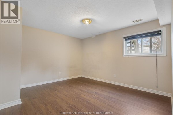 Empty room with laminate floors and a window - 219 Greenfield Lane Chatham