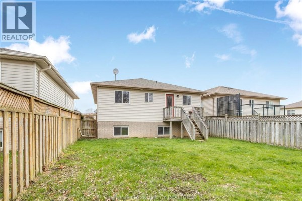 House exterior with vinyl siding, brick foundation, wooden fence, and backyard - 219 Greenfield Lane Chatham