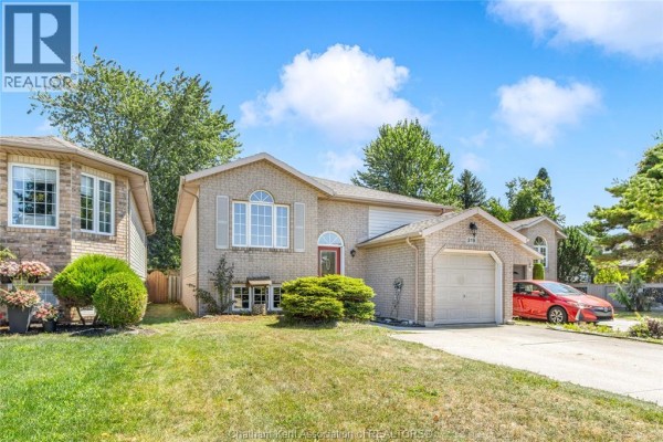 Side view of a beige brick house with a red front door and attached garage. - 219 Greenfield Lane, Chatham