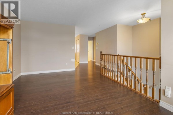 Hallway with dark hardwood floors and wooden banister - 219 Greenfield Lane Chatham