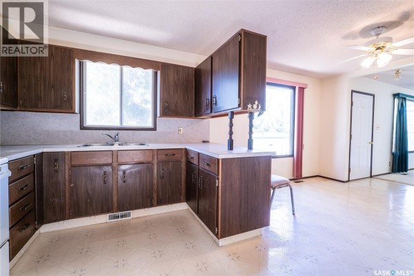 Kitchen corner view showing dark wood cabinets, sink, and window. - 219 Railway Avenue W, Blaine Lake