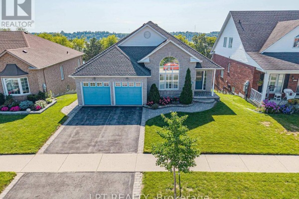 Aerial view of a detached brick house with a double garage and water in the background. - 219 Waterbury Crescent, Scugog
