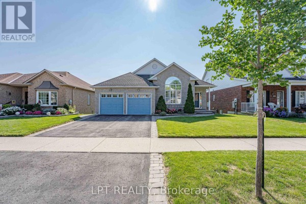 Front view of a detached brick house with a double garage and sidewalk. - 219 Waterbury Crescent, Scugog