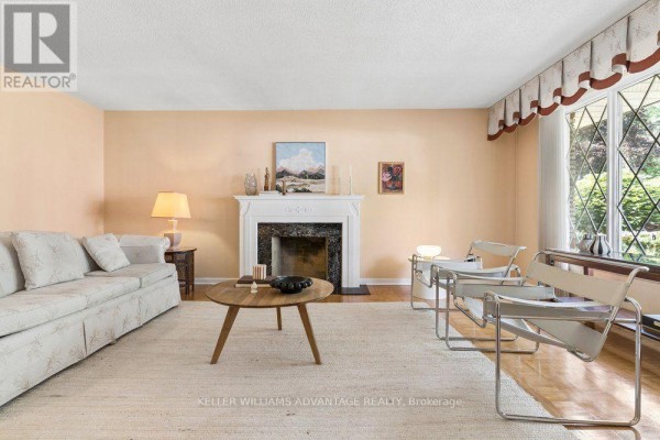 Living room with red carpet, brick fireplace, and wood paneling accents. - 2192 Castlestone Court, Mississauga