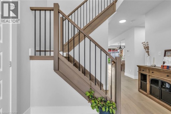 Interior view of a wooden staircase with black spindles and a console table with decor. - 2195 Ironwood Road, London