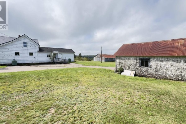 View of a white house and several agricultural outbuildings with metal roofs on a sunny day. - 2195 Windham Hill Road, Windham Hill
