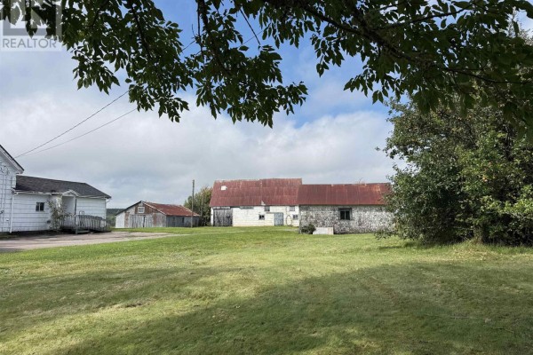 A white house and agricultural buildings with metal roofs are set against a green lawn and trees. - 2195 Windham Hill Road, Windham Hill