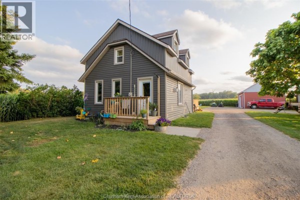 Front view of a dark gray house with a wooden porch and green lawn. - 21956 Charing Cross Road, Charing Cross