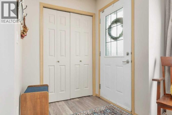 Interior entryway with white bi-fold doors, a frosted glass front door, and a bench. - 22, 33 Jennings Crescent, Red Deer