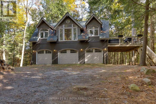 Exterior of a multi-story wooden cottage with multiple garage doors and a large upper deck. - 22 - 1213 Camp Jackson Road, Muskoka Lakes
