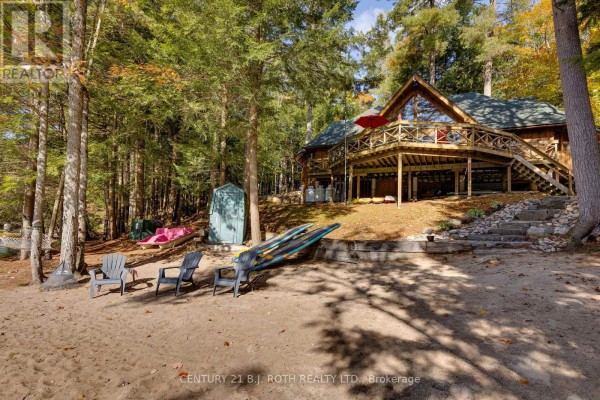 Cozy bedroom with vaulted ceiling, fireplace, leather sofas, and a wooden bed frame. - 22 - 1213 Camp Jackson Road, Muskoka Lakes