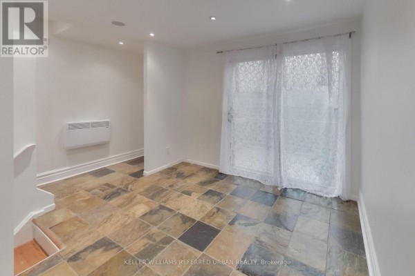 Kitchen area with a breakfast bar, two stools, and a refrigerator. - 22 - 1666 Queen Street E, Toronto