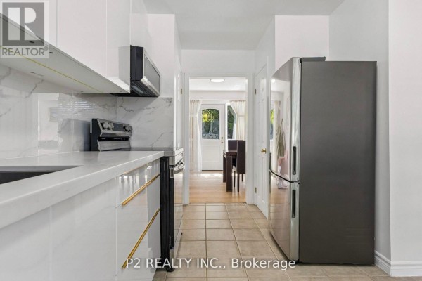 View from the kitchen towards a dining area with a stainless steel refrigerator. - 22 - 22-25 Gosford Boulevard N, Toronto