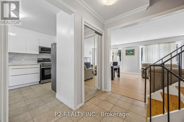 View from the hallway into the kitchen and living area with a staircase. - 22 - 22-25 Gosford Boulevard N, Toronto