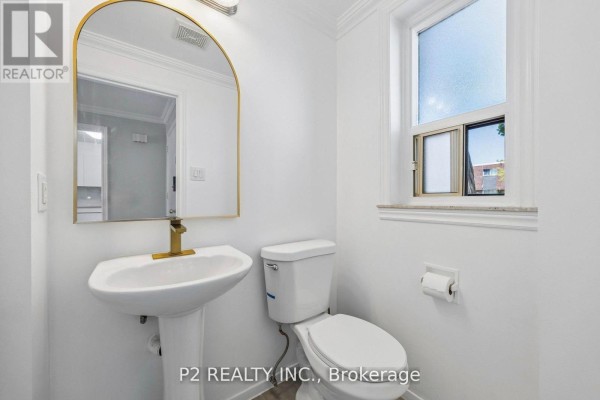 Powder room with a white pedestal sink, toilet, and arched mirror. - 22 - 22-25 Gosford Boulevard N, Toronto