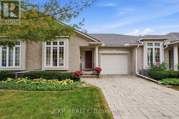 Exterior of a beige brick townhouse with a garage and paved driveway. - 22 - 3241 Montrose Road, Niagara Falls