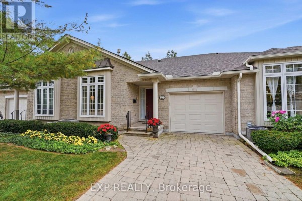 Front exterior view of a beige brick townhouse with a garage and landscaping. - 22 - 3241 Montrose Road, Niagara Falls
