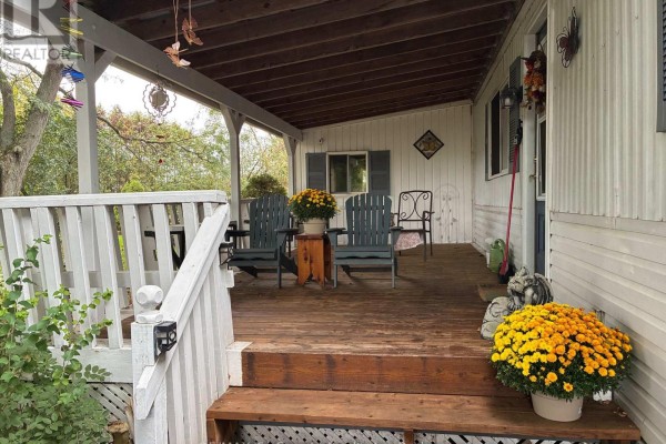 Covered wooden porch with chairs and decorative mums. - 22 - 4899 Plank Road, Bayham