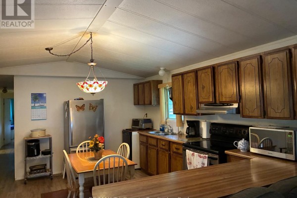 Kitchen area with stainless steel refrigerator, wooden cabinets, and a small dining table. - 22 - 4899 Plank Road, Bayham