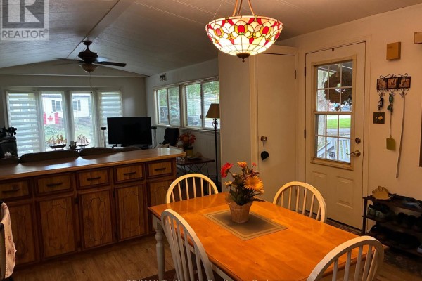 Dining area and kitchen with white chairs, a wooden table, and a stained-glass pendant light. - 22 - 4899 Plank Road, Bayham