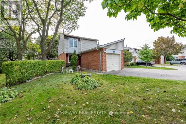 Side exterior view of townhouse 22 with a brick base and vinyl siding. - 22 - 525 Meadows Boulevard, Mississauga