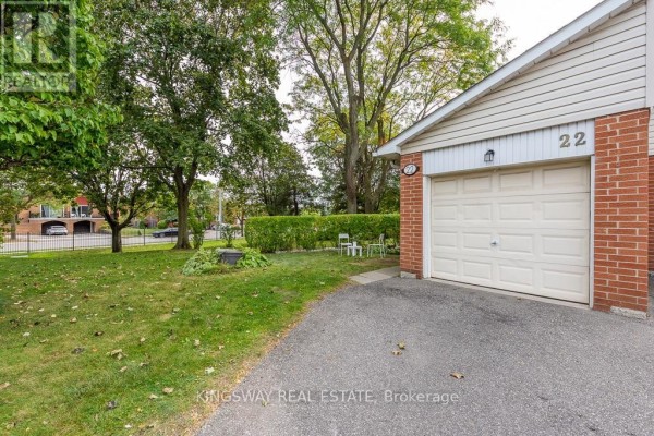 Close up of townhouse 22's garage door with a brick facade and paved driveway. - 22 - 525 Meadows Boulevard, Mississauga