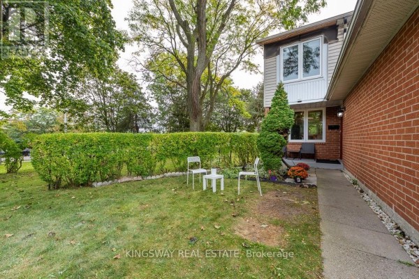 Front entrance of townhouse 22 with white chairs and a small table on the lawn. - 22 - 525 Meadows Boulevard, Mississauga