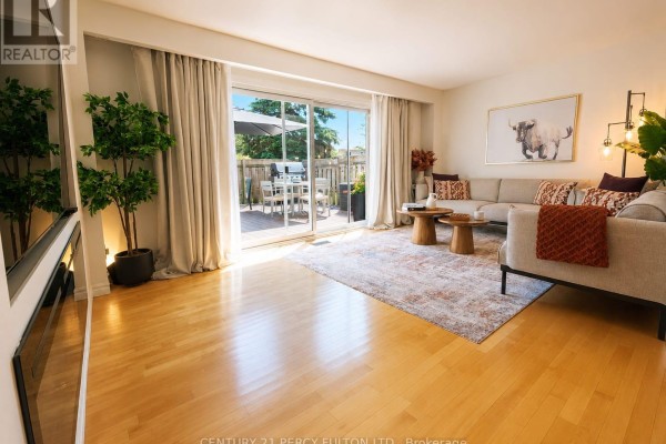 Living room with light wood floors, large sliding glass doors leading to a deck, and a sectional sofa. - 22 - 580 Eyer Drive, Pickering