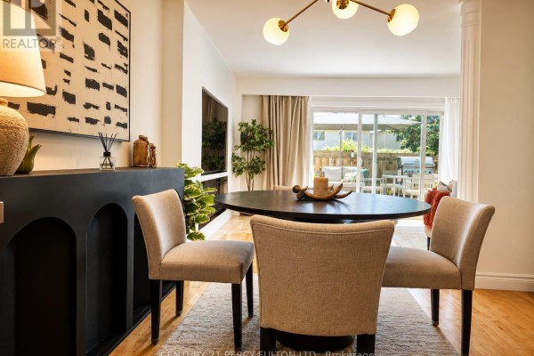 Dining area with a dark round table, four chairs, and a black fireplace surround with modern art. - 22 - 580 Eyer Drive, Pickering