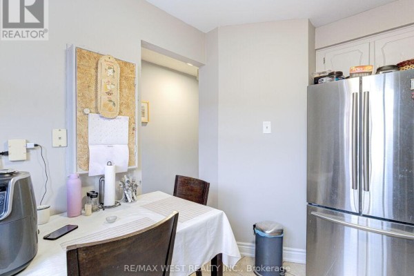 A stainless steel refrigerator stands in the corner next to a table and chairs. - 22 - 83 Irwin Road, Toronto