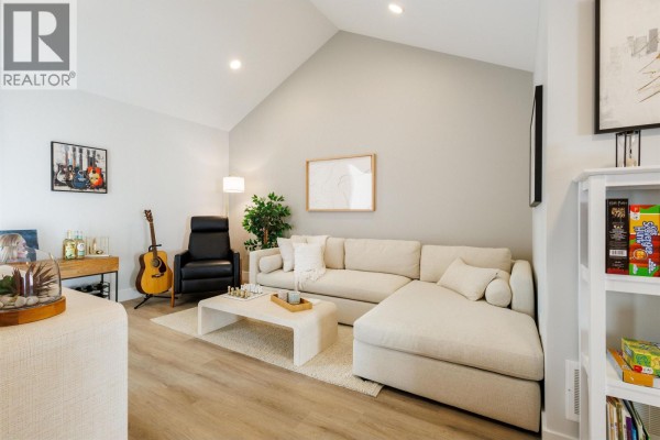 Spacious living room with vaulted ceilings, a sectional sofa, armchair, and tall window. - 22 10640 248 Street, Maple Ridge