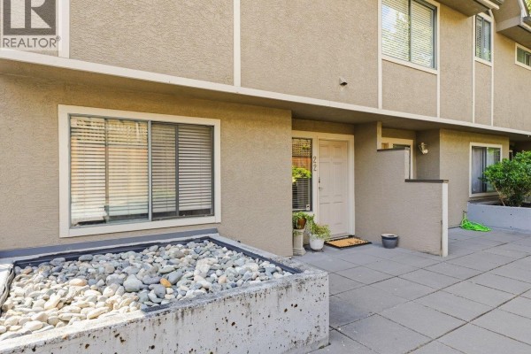 Exterior entrance to unit 22 with beige siding, a white door, and a stone planter. - 22 2133 St. Georges Avenue, North Vancouver