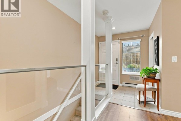 Interior entryway with tiled floor, staircase with glass railing, and beige walls. - 22 2133 St. Georges Avenue, North Vancouver