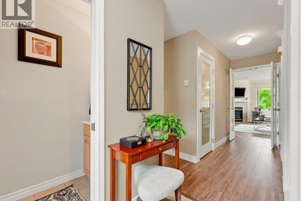 Hallway with wood flooring, beige walls, decorative table, and doorways to other rooms. - 22 2133 St. Georges Avenue, North Vancouver