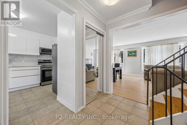 Kitchen with white cabinets, stainless steel appliances, marble backsplash, and a gray refrigerator next to a door. - 22-25 Gosford Blvd. Boulevard N, Toronto