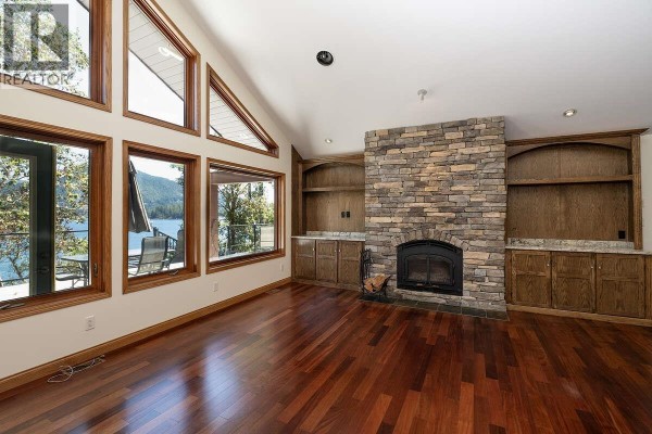 Living room featuring stone fireplace, built-in cabinetry, and water view - 22 4622 Sinclair Bay Road, Garden Bay