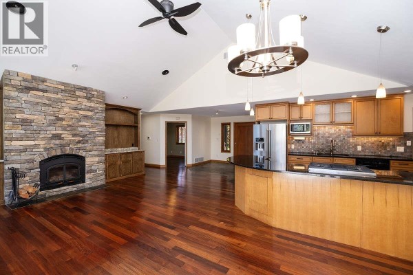 Kitchen with stone fireplace, granite countertops, and stainless steel appliances - 22 4622 Sinclair Bay Road, Garden Bay