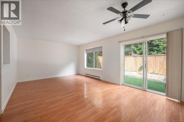 Staged living and dining area with sectional sofa, chairs, table, and backyard view. - 22 711 Malone Rd, Ladysmith