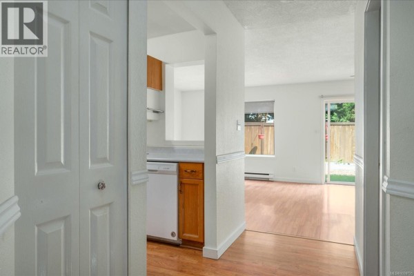 View from hallway into kitchen and living area with wood floors and white walls. - 22 711 Malone Rd, Ladysmith