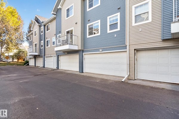 Rear exterior of townhouses showing multiple white garage doors and balconies. - #22 8304 11 Av Sw, Edmonton