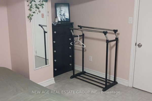 A black dresser with mirrored drawer pulls sits next to a clothing rack in a room with pink walls. - 22 Alice Street, Hamilton