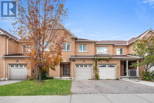 Close-up of a brick townhouse exterior showing entrance and garage doors. - 22 Bay Breeze Drive, Brampton