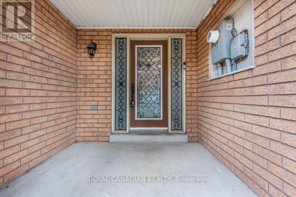 Covered porch of a brick townhouse with a glass-paneled front door. - 22 Bay Breeze Drive, Brampton